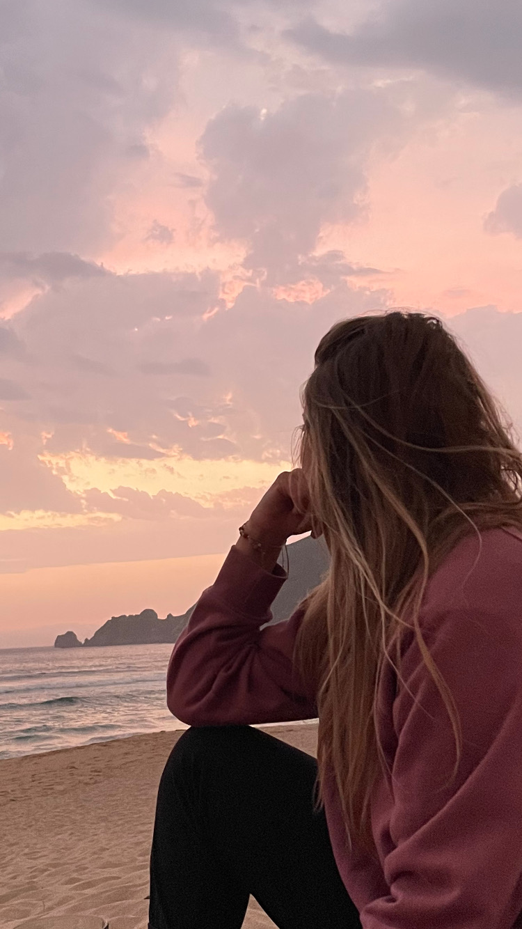 Vrouw kijkt uit over zee bij zonsondergang