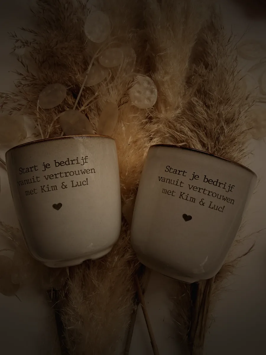 Twee handgemaakte mokken met de tekst: Start je bedrijf vanuit vertrouwen met Kim & Luc!