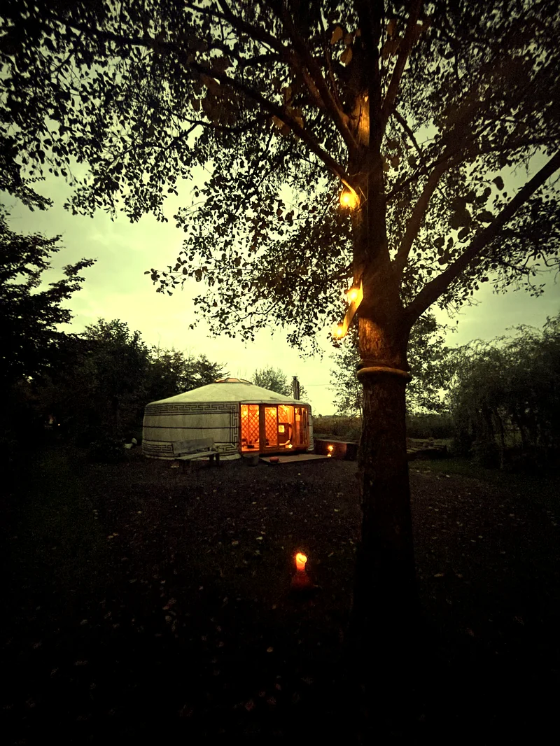 De yurt tussen de bomen met lichtjes bij avond