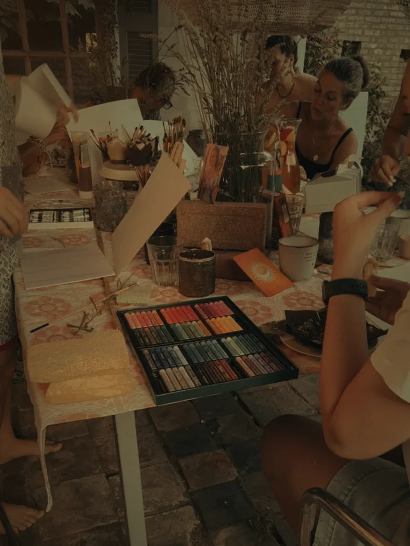 De kleurrijke tafel vol verf, pastels en bloemen